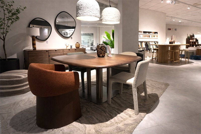 Mesa de comedor de madera oscura con sillas tapizadas y espejos decorativos en ambiente moderno. Comedor contemporáneo con mesa rectangular de madera oscura, sillas tapizadas en tonos neutros y terracota, aparador de madera y espejos redondos en la pared.